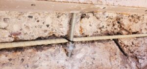 Loose concrete J-bolt anchor being repaired and replaced with a new standard anchor bolt